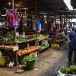 A busy Kenyan market with people shopping for food items.