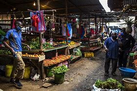 A busy Kenyan market with people shopping for food items.