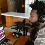 A journalist in East Africa using a laptop and smartphone for digital reporting, symbolizing media innovation.