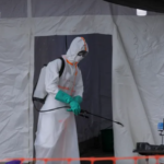 Ugandan health worker in protective gear addressing Ebola outbreak.