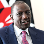 Kenyan President William Ruto dressed in a black suit and white shirt, addressing a crowd during a public rally.