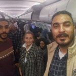 Palestinian passengers sit on a plane with hands raised, arriving in South Africa amid controversy over charter flights from Gaza