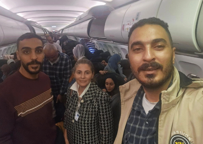 Palestinian passengers sit on a plane with hands raised, arriving in South Africa amid controversy over charter flights from Gaza