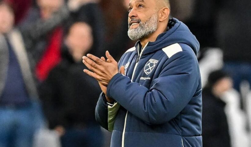 Nuno Espirito Santo smiling and holding a West Ham home shirt during his appointment as manager, standing in front of a sponsors board