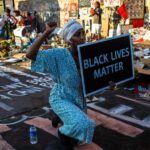 US President Donald Trump speaking at a public event, captured mid-speech against an official backdrop.