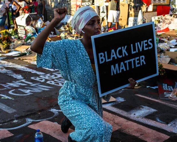 US President Donald Trump speaking at a public event, captured mid-speech against an official backdrop.