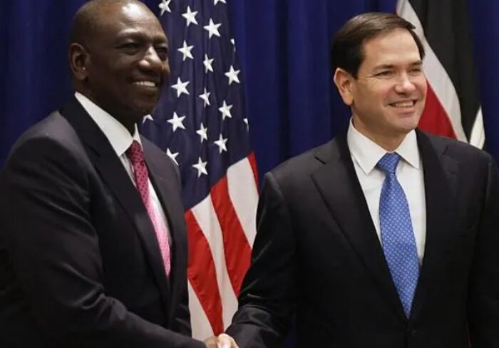 US Secretary of State Marco Rubio and Kenyan President William Ruto shake hands in Nairobi during the signing of a new Kenya–US health partnership, with both nations’ flags in the background.